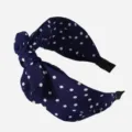 Primo piano dettaglio della fascia per capelli in tessuto a pois blu scuro morbido. - Blu navy