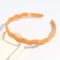 Détail en gros plan d'un cerceau à cheveux ondulé orange minimaliste pour un usage quotidien. - Curcuma