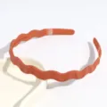 Gros plan sur le serre-tête ondulé minimaliste en plastique terracotta, accessoire idéal. - Rouge Orangé