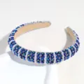 Detail view of the elegant baroque crystal rhinestone and pearl padded headband in deep blue. - Blue