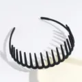 Close-up detail of a black plastic comb headband with teeth design for secure hair styling. - Black