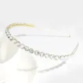 Close-up detail of a minimalist gold-toned metal headband adorned with sparkling clear rhinestones. - Rhinestone