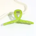Nahaufnahme der transparenten grünen Twist Haarspange mit glänzender Oberfläche und Feder. - Grün