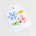 Primer plano detallado de lindas pinzas para el cabello con flores coloridas en tarjeta. - Rosa+Azul
