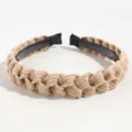 Detalle de diadema trenzada marrón con textura de pana suave y aro interior de plástico negro. - Caqui