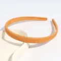 Gedetailleerd overzicht van de stijlvolle oranje kunststof haarband met subtiele keperstructuur. - Gembergeel