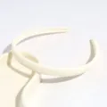 Inquadratura dettagliata di un cerchietto minimalista in plastica bianca a spina di pesce. - Beige