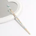 Elegant blue white swirl acetate hair stick resting on a white decorative mirror detail view. - White Yellow