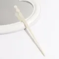 Detailed shot of an elegant white acetate hair stick, showcasing its smooth pearlescent texture. - Ivory