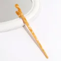 Close-up detail of an amber acetate twisted hairpin, elegant vintage hair accessory style. - Gold