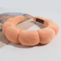 Detailopname van de zachte oranje haarband van sponsstof, pluizige texture en mooie kwaliteit. - Oranje