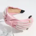 Detailopname van een roze satijnen haarband met knoop, versierd met parels en mooie strass. - Roze