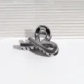 Detailansicht der kleinen metallischen Haarklammer mit glänzender geometrischer Form. - Kreuz Dunkelgrau