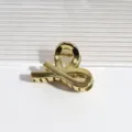Nahaufnahme einer stilvollen goldenen Haarspange aus Metall mit einzigartigem Schlaufendesign. - Kreuz Gold