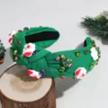 Close-up detail shot of green knotted Christmas headband featuring rhinestones and holiday charms. - Santa Claus Green
