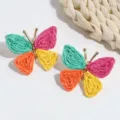 Close-up shot of colorful straw-woven butterfly stud earrings featuring vibrant woven wing details. - Green Orange Yellow Purple Butterfly