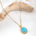 Close-up detail of a gold-plated oval turquoise pendant necklace with sparkling cubic zirconia. - Gold Oval Turquoise