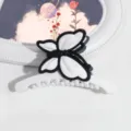 Primo piano dell'elegante molletta per capelli a farfalla in bianco e nero dal design opaco. - Stile Farfalla / Bianco