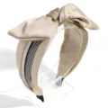 Close-up of elegant wide satin bow headband featuring classic houndstooth and rhinestone trim. - Champagne