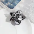 Close-up van een stijlvolle zilveren bloem haarclip op een wit bord met metallic glans. - Donkergrijze Spiraalbloem