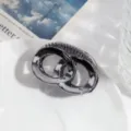 Detailopname van donkerzilveren geometrische haarclip met in elkaar grijpende ringen textuur. - Donkergrijze Ketting
