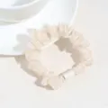 Gros plan détail d'un chouchou à cheveux en satin beige avec design plissé et anneau blanc. - Gaze Beige