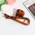 Primer plano detallado de una elegante pinza para el pelo con carey para peinados diarios. - Estilo Cruz Geométrica / Estampado de leopardo ámbar