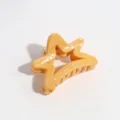 Close-up detail of a yellow star-shaped hair claw clip featuring stylish silver splatter design. - Star / Yellow