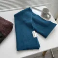 Nahaufnahme des blauen Rippstrickschals mit weicher Textur und sauberem Etikettendesign. - 180cm / Blaugrün