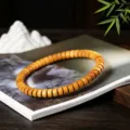 Detailansicht eines natürlichen goldenen Sandelholz-Tablettenperlenarmbands mit Textur - 4x7mm (Premium-Stil) / Goldenes Sandelholz Tablet