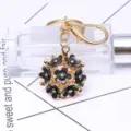 Eleganter vergoldeter Schlüsselanhänger mit hohlem schwarzen Emaille-Blumenball-Anhänger - Schwarz