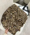 Dettaglio di un elegante foulard di seta quadrato con stampa leopardata su una sedia bianca. - Leopardo marrone