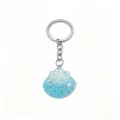 Close-up detail of a cute blue glitter seashell keychain with a durable silver metal ring. - Blue