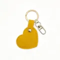 Close-up of yellow heart-shaped leather keychain pendant, showing fine stitching and metal keyring. - Yellow