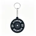 Close-up detail of the mini barbell weight plate keychain pendant, showing textured PVC surface. - Black