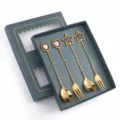 Set di cucchiai e forchette dorate con ciondoli a stella e cuore in elegante confezione. - Set da 4 pezzi con ciondoli misti 304 - scatola verde