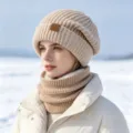 Close-up of a beige knitted beanie and fleece-lined neck warmer on a model in snow. - One Size / Set / Beige