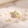 Detail shot of light luxury titanium steel gold-plated ring with green and purple gemstones. - Birthstone - August