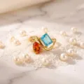 Stunning double stone ring featuring orange and blue gems in a gold-plated modern setting. - Birthstone - December