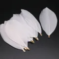 White DIY craft feathers with gold metal clips for jewelry making and apparel decoration projects. - White