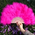 Grand éventail en plumes rose vif avec des côtes en bois sculptées pour spectacles et fêtes. - Rose rouge