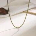 Detail shot of a delicate gold-toned claw chain necklace with dark crystal rhinestones. - Green Rhinestone Necklace - Gold