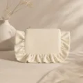 Close-up detail of corduroy cosmetic bag featuring elegant fabric ruffles and secure metal zipper. - Creamy White