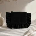 Detailed closeup view of black corduroy cosmetic pouch featuring elegant ruffled edge. - Black