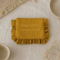 Detailansicht der senfgelben Nylon Kosmetiktasche mit Rüschen und feiner Stickerei. - Kurkuma / 22*17CM