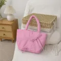 Dettaglio della borsa rosa plissettata con fiocchi carini in un ambiente domestico accogliente. - Rosa