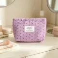 Dettaglio borsa cosmetica in tessuto viola con stampa di stelle ed etichetta frontale. - Viola con piccole stelle