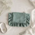 Detailed shot of green corduroy cosmetic bag featuring elegant ruffled trim and smooth zipper. - Grass Green