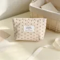 Primo piano di una graziosa borsa cosmetica in tela con stampa di stelle e piccola etichetta. - Beige con stelle marroni