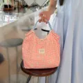 Nahaufnahme einer rot-weiß karierten Stofftasche mit Schleifen und blauen Griffen. - Karomuster Rote Schleife